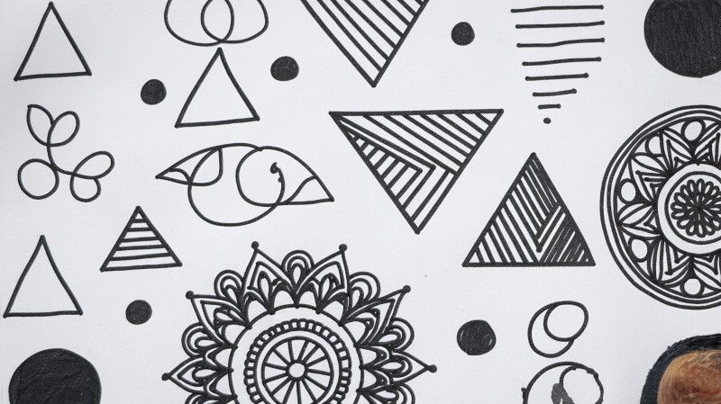 drawing paper with simple shapes, lines, and mandalas sketched on it